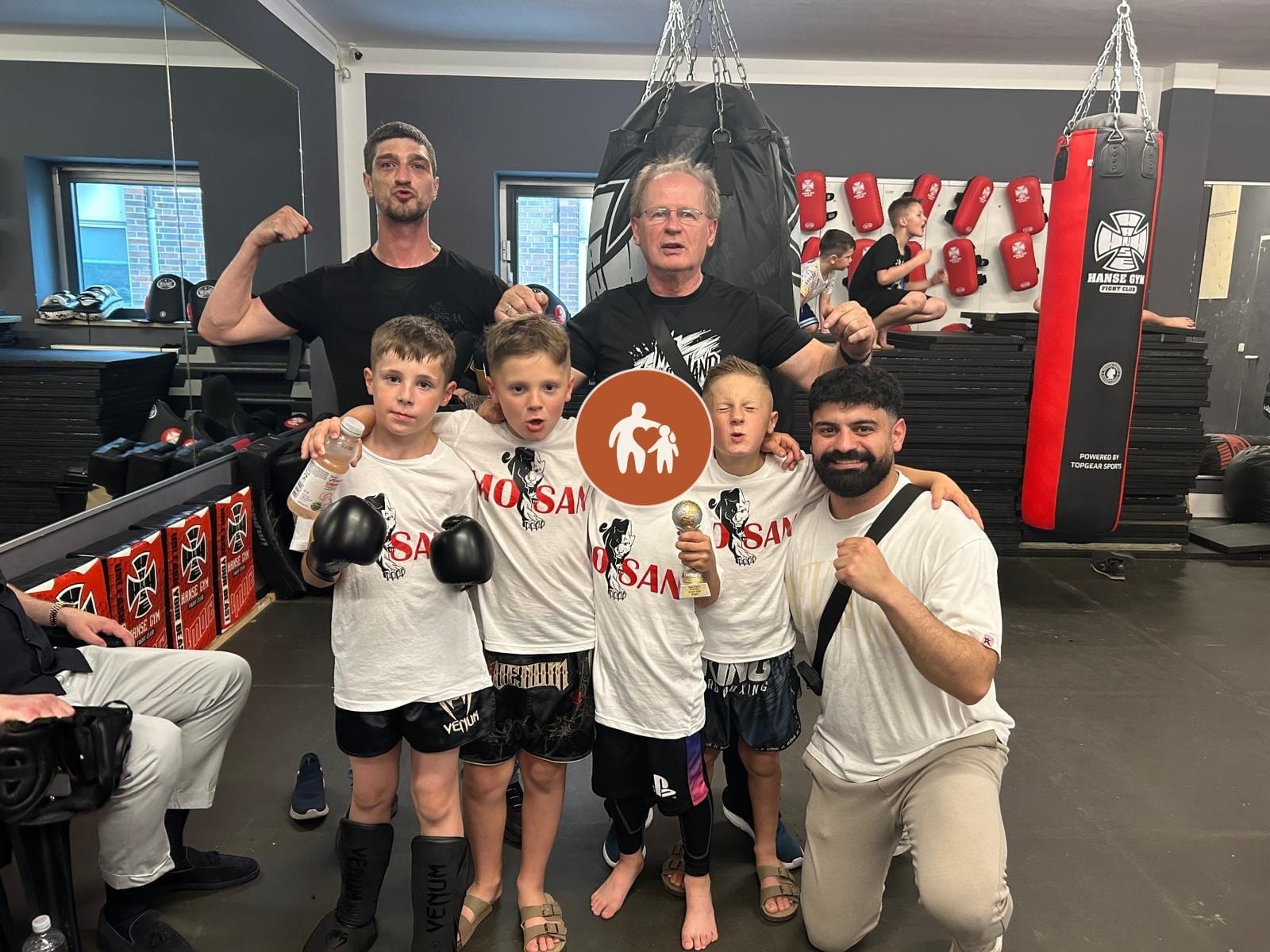 Gruppe von Jungen mit Boxhandschuhen und zwei Trainern im Trainingsraum